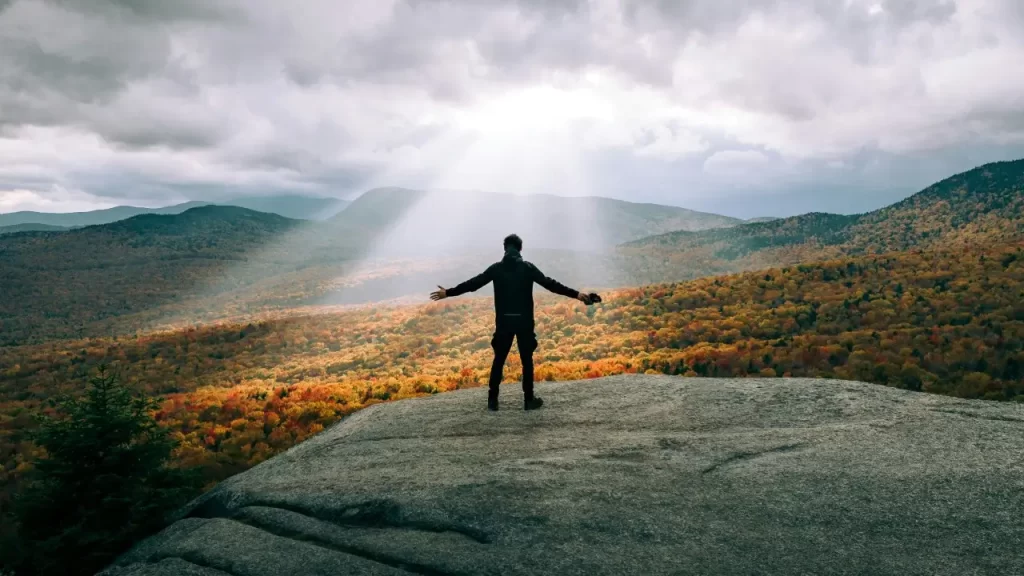 homem sob um raio de sol na montanha