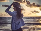 Mulher olhando para o horizonte ao pôr do sol, com expressão de liberdade, leveza e esperança, representando autoconhecimento e conexão com a vida. cura emocional e trasformação