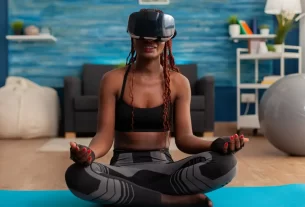 mulher-jovem-experimentando-realidade-virtual-treinando-corpo-e-mente-meditando-na-posicao-de-lotus-sentada-no-tapete-de-ioga-na-sala-de-estar-de-sua-casa-
