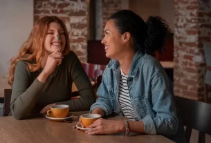 “Duas amigas conversando e rindo ao ar livre, com celulares desligados, representando conexões autênticas e relações verdadeiras na era digital