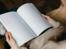 Mulher sorrindo enquanto segura um livro em branco, representando o poder de escrever sua própria história e assumir sua transformação pessoal.” melhor livro de autoajuda do mundo