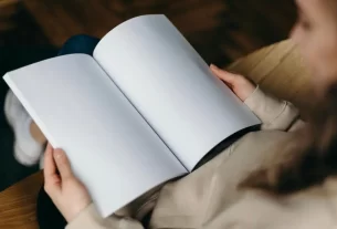 Mulher sorrindo enquanto segura um livro em branco, representando o poder de escrever sua própria história e assumir sua transformação pessoal.” melhor livro de autoajuda do mundo