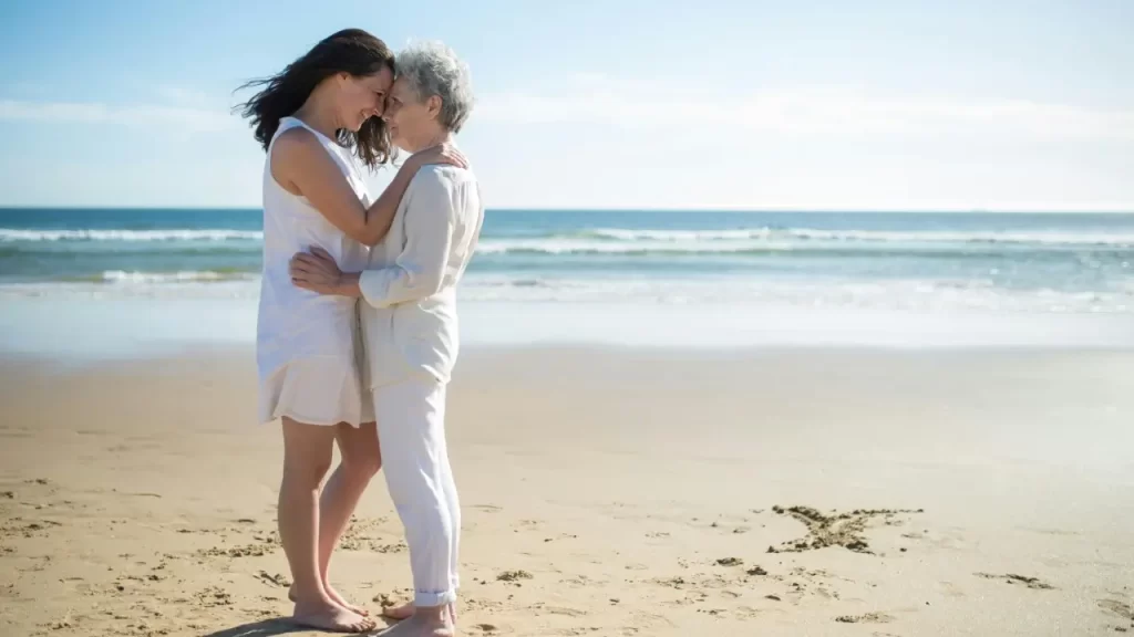mãe e filha abraçadas a  beira mar