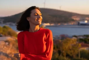 Mulher feliz, conectada consigo, simbolizando amor-próprio e energia elevada.