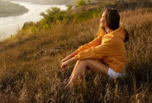 Mulher meditando em contato com a natureza, representando a espiritualidade naturalista e conexão interior. tipos de espiritualidade