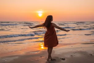 mulher de braços abertos em campo iluminado pelo nascer do sol, representando o renascimento da mulher na nova era