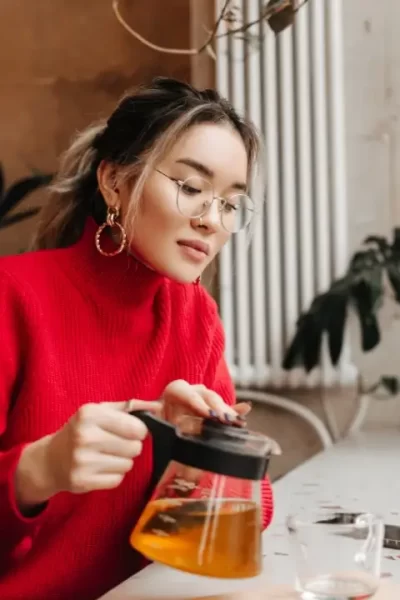 Mulher preparando chá de ervas medicinais no jardim, prática de fitoterapia para cura natural comprovada pela ciência.