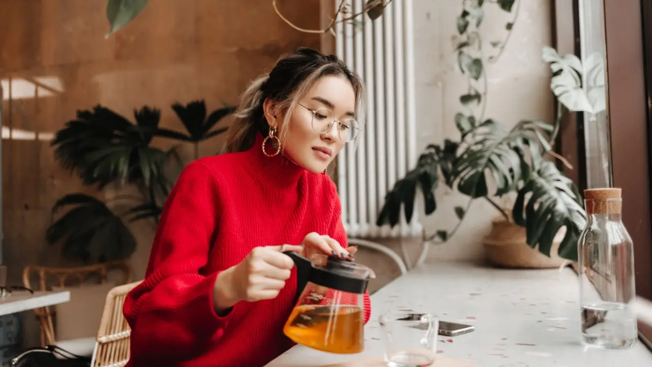 Mulher preparando chá de ervas medicinais no jardim, prática de fitoterapia para cura natural comprovada pela ciência.